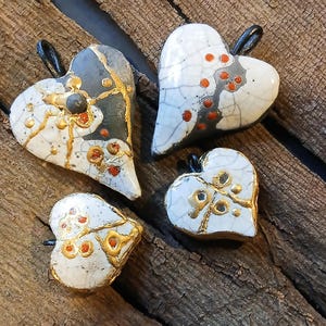 Zwart-witte hartvormige hanger gemaakt met de raku kintsugi-techniek.