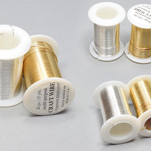 Könnte beinhalten: Vier Spulen mit 20 Gauge Bastel-Draht, zwei gold und zwei silber, jede mit 13,7 Metern Draht. Die Spulen sind mit "CRAFT WIRE" und "TARNISH RESISTANT" beschriftet.