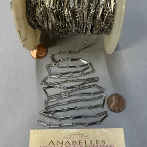 May include: A spool of silver-toned chain with a close-up of the chain links. The chain is made of small, rectangular links. The chain is on a white spool. The spool is on a gray surface. The chain is 134.  Anabelles Vintage Beads & Findings 305 E. 9th St. Suite #134 Los Angeles, CA 90015 Tel: 562-334-6919 Hours Mon-Fri 10AM - 3:30 Sat 10AM - 2:00PM
