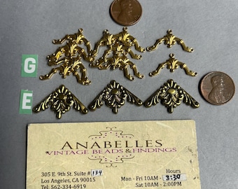May include: Gold-toned metal corner embellishments with ornate designs. The embellishments are arranged in a row on a white surface. The image also includes a business card for Anabelles Vintage Beads & Findings, located in Los Angeles, California.