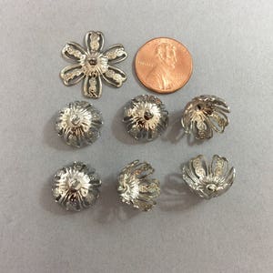 Metal findings. NOS. Filigree bead caps. Silver tone. Sold by lots of 12 pieces.