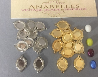 May include: A collection of 10 silver and 10 gold oval-shaped metal bezel settings with a scalloped edge. The bezels are designed to hold a cabochon stone. There are also four colorful cabochon stones in the image: a white, a green, a purple, and a blue.