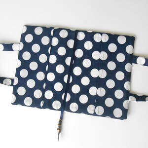 May include: A blue and white polka dot fabric book cover with two handles and a blue ribbon bookmark.