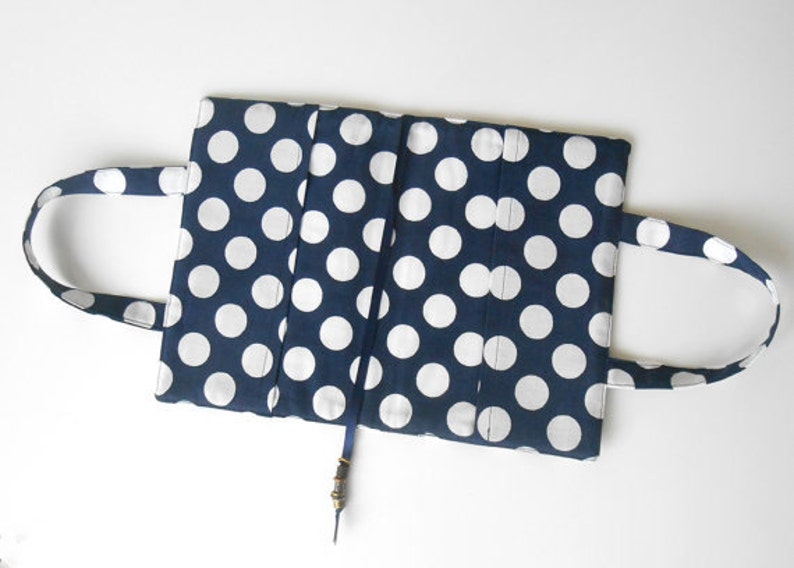 May include: A blue and white polka dot fabric book cover with two handles and a blue ribbon bookmark.
