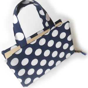 May include: A blue and white polka dot fabric tote bag with a handle. The bag is empty and has a light brown lining.