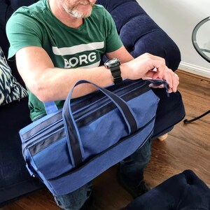 May include: A blue canvas travel bag with black trim and a zipper closure. The bag has a top handle and a shoulder strap.
