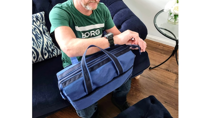 May include: A blue canvas travel bag with black trim and a zipper closure. The bag has a top handle and a shoulder strap.