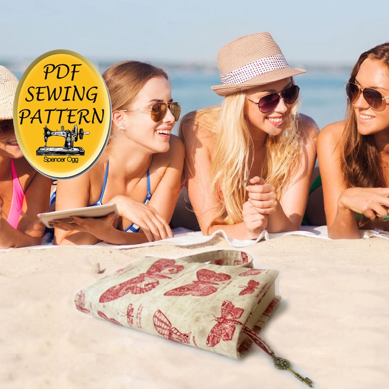 May include: A PDF sewing pattern for a butterfly-themed book cover. The pattern is available for download and includes instructions for creating a book cover with a vintage-inspired butterfly design. The cover is made of a beige fabric with red butterflies printed on it. The cover is shown on a beach with three women wearing sunglasses and swimwear.