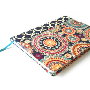 May include: A blue notebook with a colorful mandala pattern cover and a turquoise ribbon bookmark.
