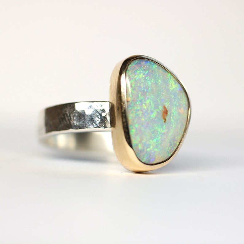May include: A silver ring with a hammered band and a gold setting featuring a green opal gemstone.
