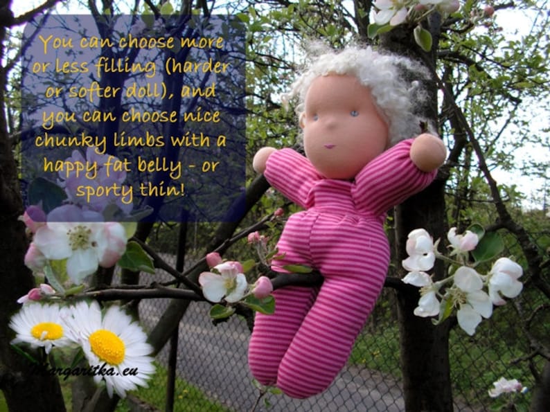 May include: A handmade doll with white yarn hair, wearing a pink and white striped outfit, sitting in a tree branch with white blossoms. The doll has a happy expression and a rosy complexion. The text "You can choose more or less filling (harder or softer doll), and you can choose nice chunky limbs with a happy fat belly - or sporty thin!" is visible in the image.