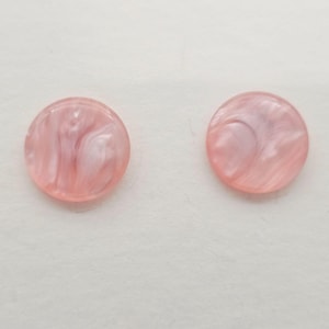 May include: Two round, pink buttons with a marbled, swirled design. The buttons have a glossy finish and are set against a white background. These buttons are ideal for sewing, crafting, or adding a decorative touch to garments.