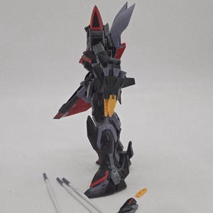Peut inclure: Un mod&egrave;le d&eacute;taill&eacute; de robot, principalement noir avec des touches de rouge et de jaune. Le robot pr&eacute;sente un design complexe avec des parties articul&eacute;es, notamment des ailes et des armes. Plusieurs pi&egrave;ces d&eacute;tach&eacute;es sont visibles.