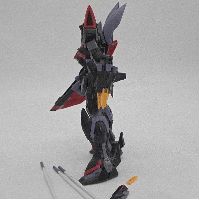 Peut inclure: Un mod&egrave;le d&eacute;taill&eacute; de robot, principalement noir avec des touches de rouge et de jaune. Le robot pr&eacute;sente un design complexe avec des parties articul&eacute;es, notamment des ailes et des armes. Plusieurs pi&egrave;ces d&eacute;tach&eacute;es sont visibles.