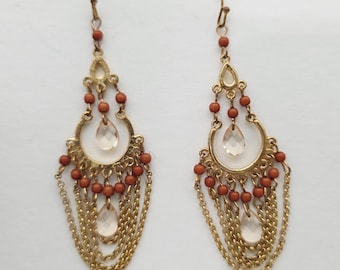 Pendientes colgantes estilo boho en tono dorado con cadenas, cuentas y detalles de cristal transparente.