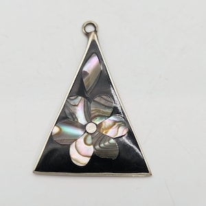 May include: A triangular pendant with a black background and a silver border. The pendant features a flower design made of iridescent abalone shell. The pendant has a small loop at the top for a chain.