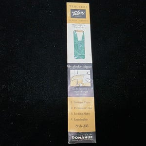 May include: A Talon zipper package for trousers and shorts. The package is white and gold with the Talon logo and the words "SLACKS SHORTS". The package shows a Kelly Green zipper, 11 inches long, and includes instructions.