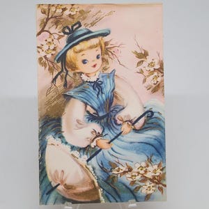 Hermosa tarjeta de felicitación vintage con vestido azul de niña y paraguas, arte de EE. UU., década de 1960