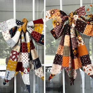 May include: Two decorative bows made from patchwork fabric squares. The left bow features red, white, blue, and yellow patterns with stars and floral motifs. The right bow displays autumn-themed colors including orange, brown, and gold with leaf prints.
