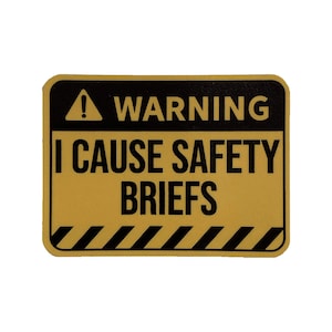 May include: A yellow warning sign with black text and a black exclamation point. The sign reads "WARNING I CAUSE SAFETY BRIEFS".