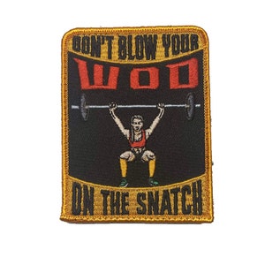 Pode incluir: Um remendo bordado dourado com fundo preto que mostra uma mulher levantando uma barra com o texto "Don't Blow Your WOD On The Snatch".