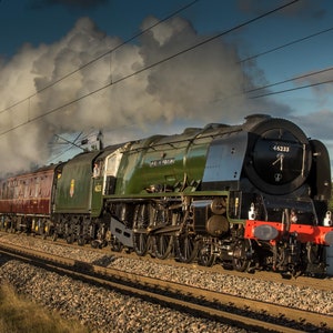 May include: A green and black steam locomotive with the number 46233 on the side, pulling a train of red passenger carriages. The locomotive is emitting a large plume of white smoke.