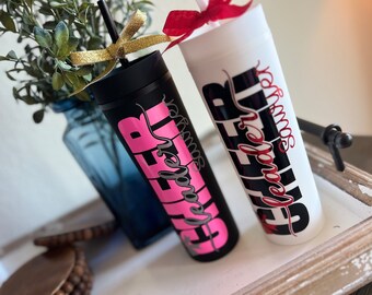 Könnte beinhalten: Zwei schwarze und weiße Becher mit dem Wort "CHEER" in Schwarz und den Wörtern "leader" und "squad" in Pink und Rot.