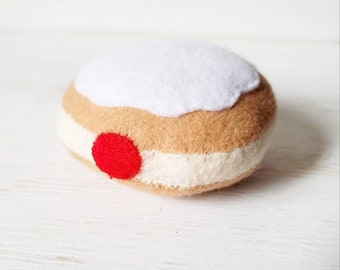 Puede incluir: Un donut de fieltro con glaseado blanco y una cereza roja en la parte superior.