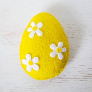 May include: A yellow felt Easter egg with three white felt flowers.