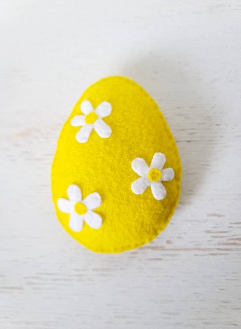 May include: A yellow felt Easter egg with three white felt flowers.