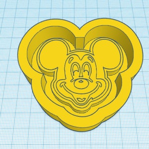 May include: Yellow plastic cookie cutter shaped like Mickey Mouse's head. The cutter has a detailed outline of Mickey Mouse's face, including his ears, eyes, nose, and smile.