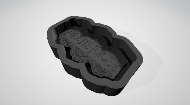 May include: Black silicone mould for making a cake or cookie in the shape of a tombstone with the words "Beetlejuice" on it.