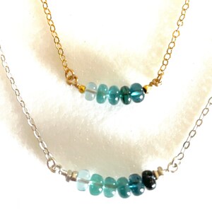 May include: Two delicate necklaces with graduated blue gemstone beads. The top necklace has a gold chain and the bottom necklace has a silver chain.