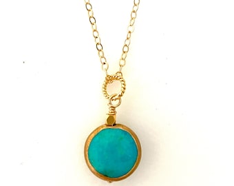 Peut inclure: Un collier en chaîne dorée avec un pendentif en pierre turquoise. Le pendentif est rond et a une bordure dorée.