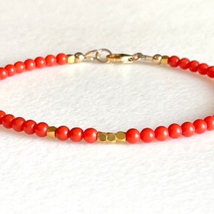 Pode incluir: Uma pulseira delicada com pequenas contas redondas de cor coral. Contas geom&eacute;tricas douradas e um fecho dourado adicionam contraste. A pulseira foi projetada para uma est&eacute;tica minimalista.
