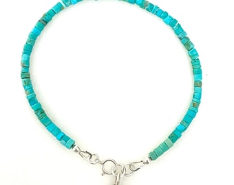 May include: A turquoise beaded bracelet with a silver heart charm. The bracelet is made of small, square turquoise beads and has a silver clasp.