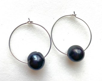 May include: A pair of silver hoop earrings with black pearl accents.