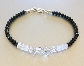 May include: A black and white beaded bracelet with a silver clasp. The bracelet features black onyx beads and clear quartz crystals.
