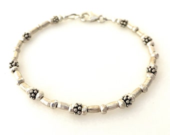 May include: A silver bracelet with a chain link design and small, round, textured beads.