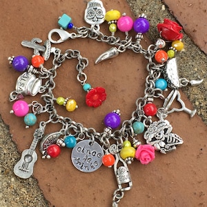Könnte beinhalten: Ein silbernes Armband mit bunten Perlen und Charms, darunter ein Totenkopf, ein Kaktus, eine Gitarre, ein Margarita-Glas, eine Tequila-Flasche, eine Blume und ein Anhänger mit der Aufschrift "Cinco de Drinko".