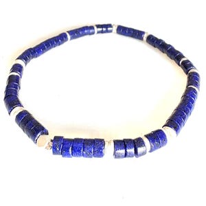 May include: A necklace featuring dark blue, disc-shaped beads interspersed with silver-colored metal spacers. The beads are strung together to form a circular shape, suitable for wearing around the neck. The necklace is set against a white background.