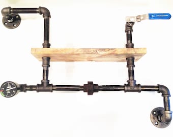 Pode incluir: Prateleira de parede em estilo industrial feita de tubos e acessórios de metal preto, com uma prateleira de madeira. Inclui um manómetro, uma válvula com pega azul e suportes de flange para fixação na parede. Design rústico único.