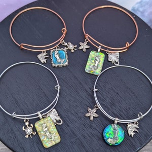 May include: Four charm bracelets with a mermaid, starfish, turtle, and stingray design. The bracelets are silver and copper in color.