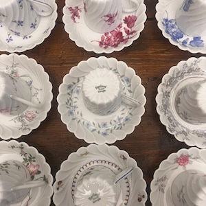 Pode incluir: Uma cole&ccedil;&atilde;o de nove x&iacute;caras de ch&aacute; e pires de porcelana branca dispostos em uma grade. Cada pe&ccedil;a apresenta uma borda recortada e uma textura nervurada em espiral. As x&iacute;caras est&atilde;o invertidas, exibindo a marca Haviland France Limoges.