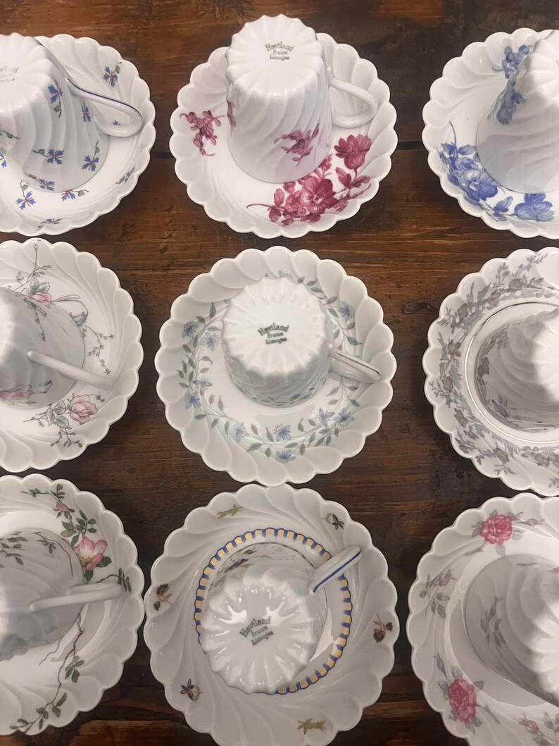 Pode incluir: Uma cole&ccedil;&atilde;o de nove x&iacute;caras de ch&aacute; e pires de porcelana branca dispostos em uma grade. Cada pe&ccedil;a apresenta uma borda recortada e uma textura nervurada em espiral. As x&iacute;caras est&atilde;o invertidas, exibindo a marca Haviland France Limoges.