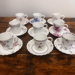 Pode incluir: Um conjunto de oito ch&aacute;venas de ch&aacute; e pires em porcelana branca, cada um com um padr&atilde;o floral &uacute;nico e uma textura nervurada em espiral. As ch&aacute;venas t&ecirc;m pegas curvas e assentam em pires a condizer com bordos recortados e desenhos bot&acirc;nicos.