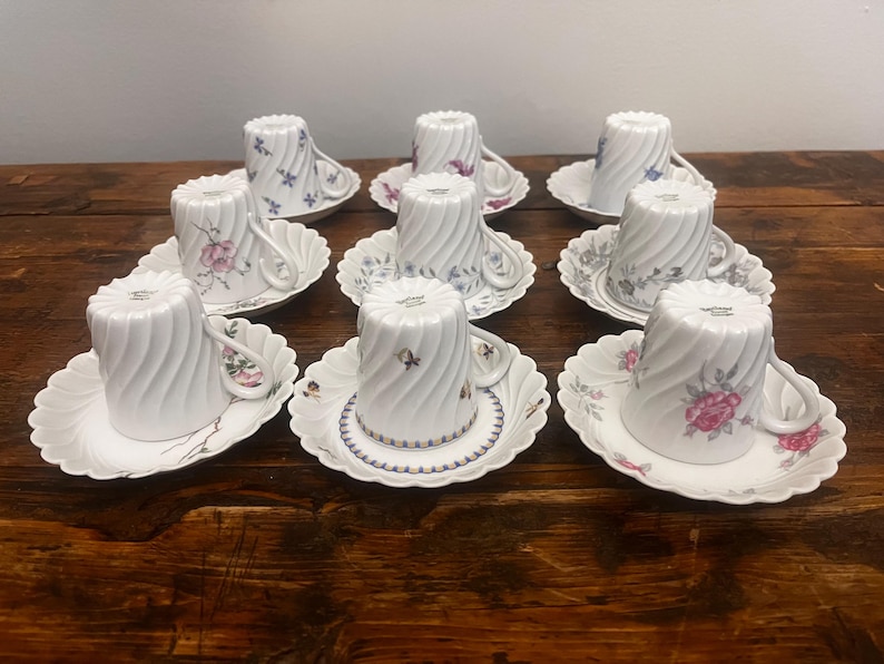 Pode incluir: Um conjunto de oito ch&aacute;venas de ch&aacute; e pires em porcelana branca dispostos em tr&ecirc;s filas. Cada ch&aacute;vena apresenta um padr&atilde;o de espiral vertical e uma asa. As ch&aacute;venas e os pires est&atilde;o decorados com v&aacute;rios motivos florais delicados.