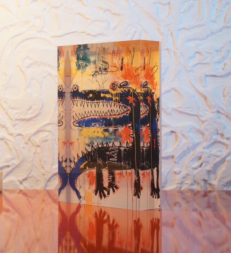 Puede incluir: Un bloque acr&iacute;lico colorido con una pintura de dos cocodrilos negros con la boca abierta y dientes afilados. El fondo es una mezcla de pintura amarilla, naranja, azul y blanca.