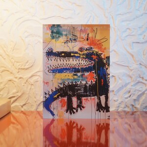 Puede incluir: Una pintura abstracta colorida de un cocodrilo negro con acentos azules y amarillos. El cocodrilo tiene una gran boca abierta con dientes afilados. El fondo es una mezcla de colores brillantes, incluyendo rojo, amarillo, verde y azul.