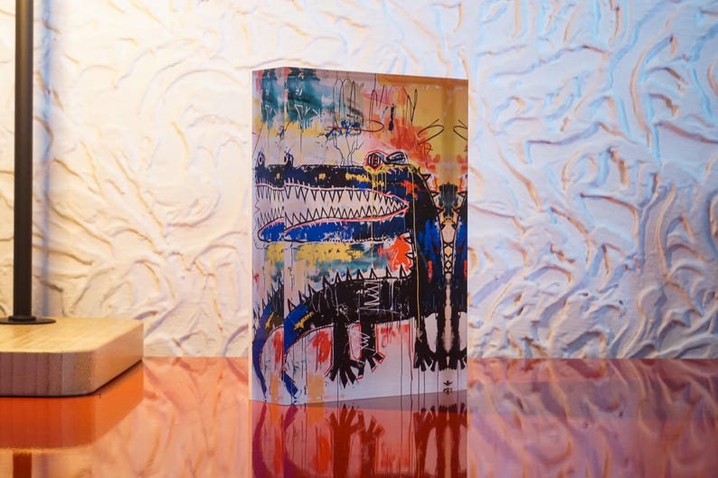 Puede incluir: Un bloque acr&iacute;lico colorido con una pintura abstracta de un cocodrilo en negro y azul. La pintura est&aacute; sobre un fondo blanco con salpicaduras de pintura amarilla, roja y naranja.